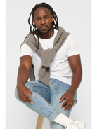 Man wearing a gray sweater over a premium cotton white t-shirt with blue jeans on a white background