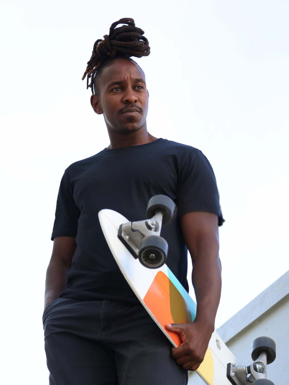 Man wearing breathable cotton t-shirt made from Oeko-Tex fabric in South Africa by BREETH. Designed for all-day comfort, durability, and effortless everyday style. Holding a colorful skateboard against a white background