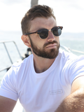Man wearing sunglasses and a breathable white cotton t-shirt with logo made from Oeko-Tex fabric in South Africa by BREETH, outdoors.