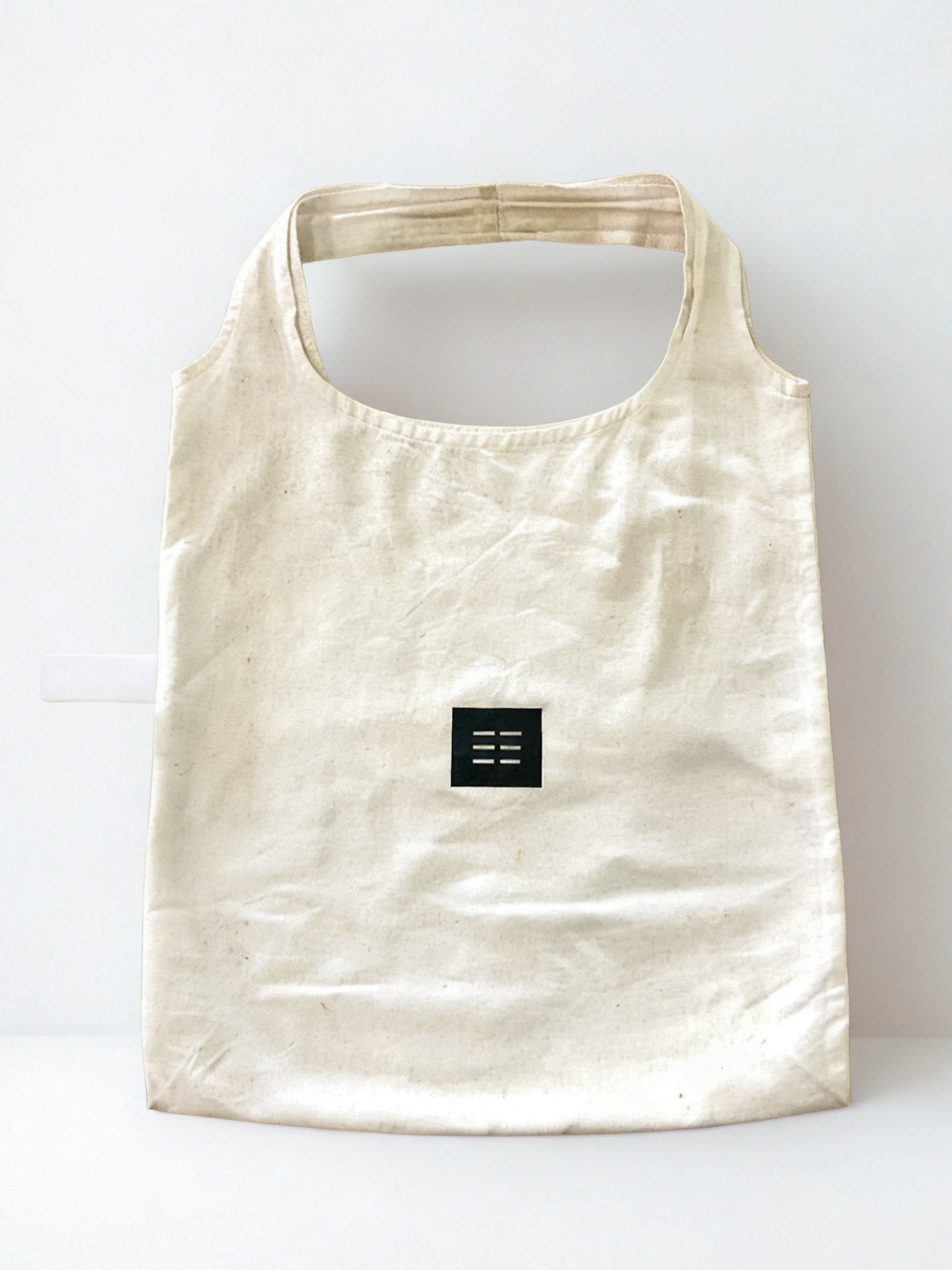 Beige reusable bag with a black logo on a white background. Eco-friendly reusable cotton shopper bag in South Africa